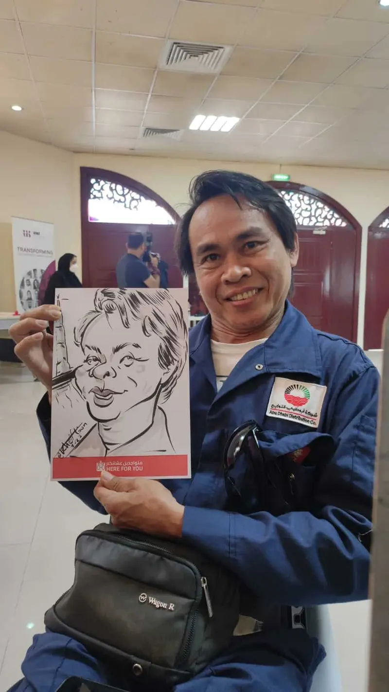 Caricature artist's hand finishing a black marker caricature of a smiling guest at a company event