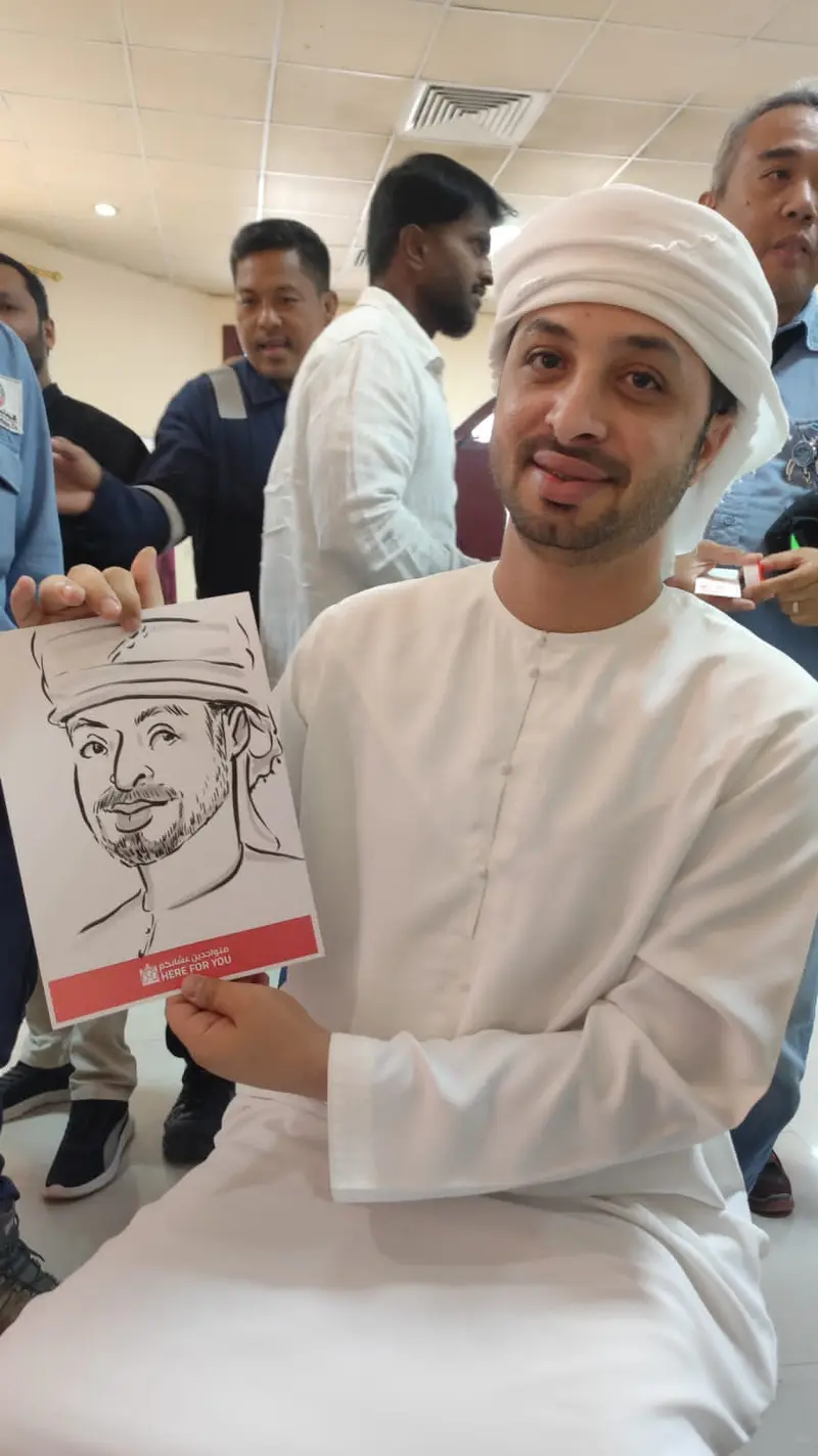 Emirati guest holding a black ink caricature drawn of him live at a corporate event