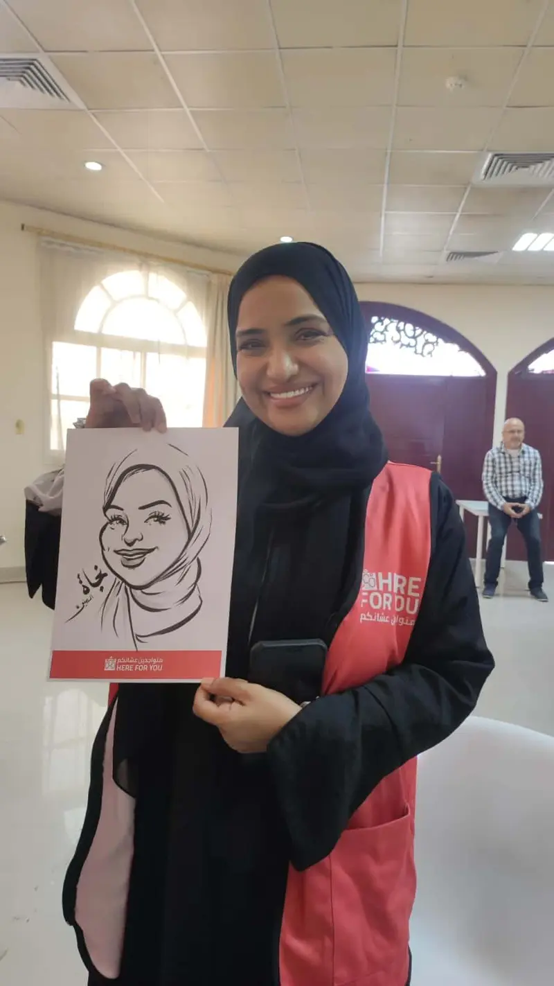 Guest in a black hijab holding her live caricature, drawn in black ink at a corporate event