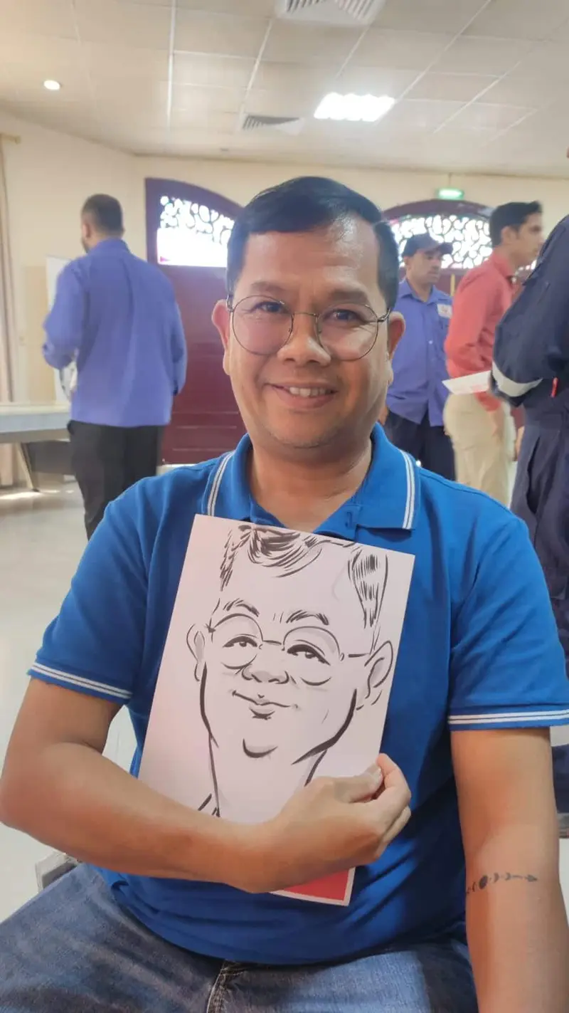 Guest in a blue polo shirt holding the caricature an artist drew of him live at a staff day