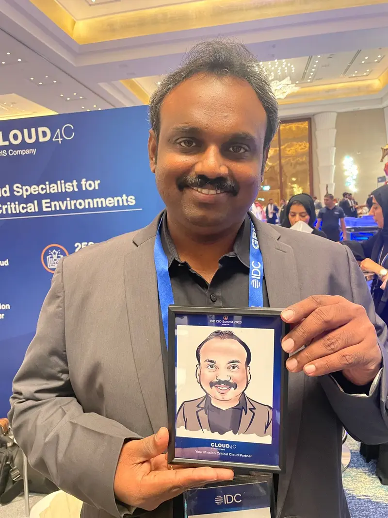 Visitor at an exhibition stand holding a framed colour digital caricature drawn of him at the event